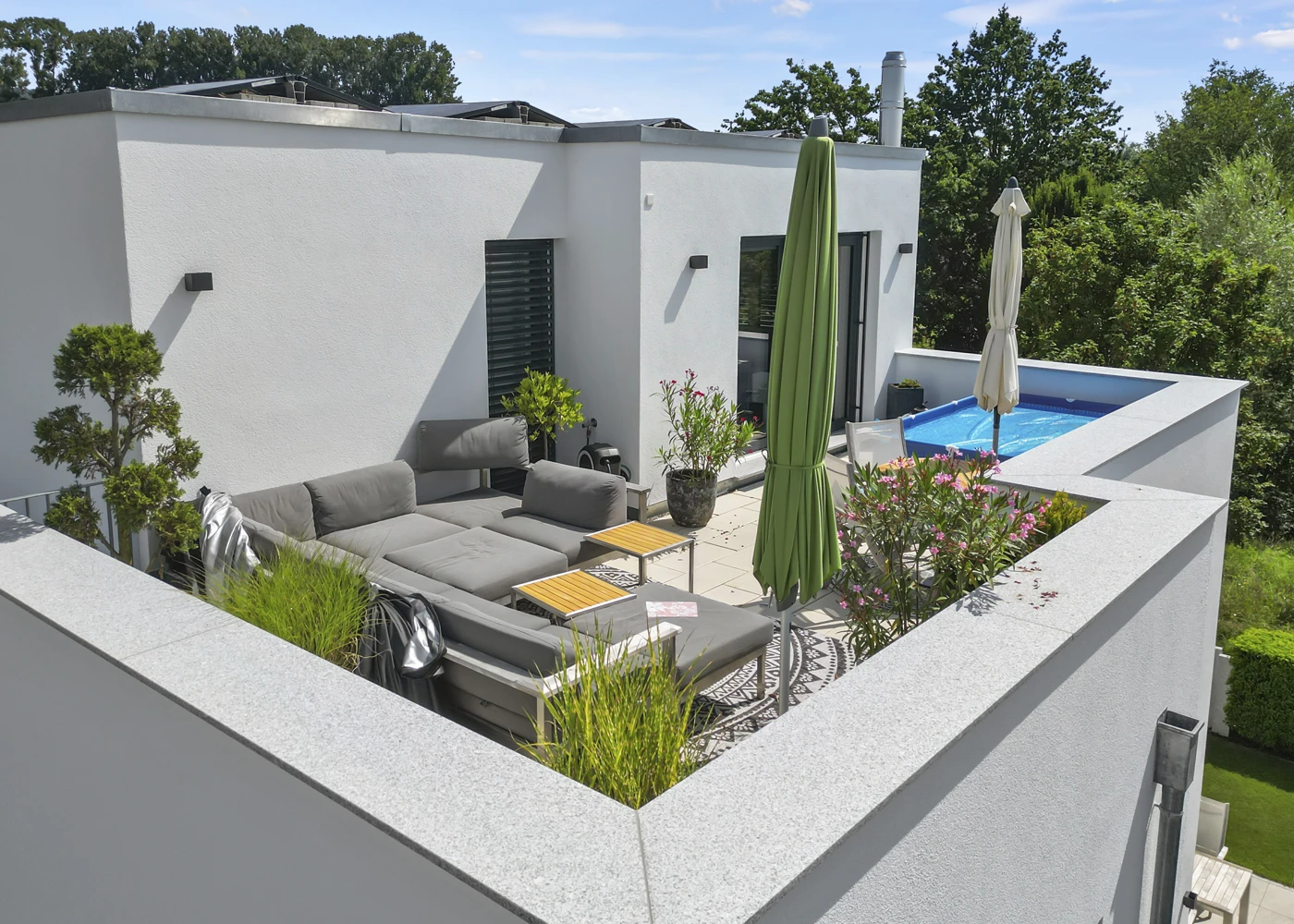 Moderne Dachterrasse mit gemütlicher Sitzecke, Sonnenschirm und kleinem Pool.