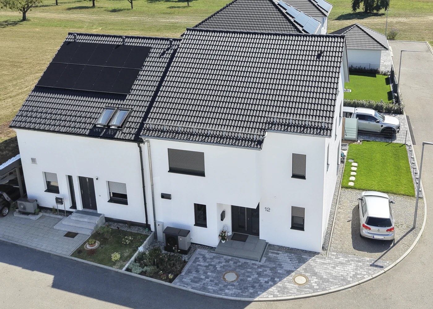 Moderne, Doppelhaushälfte und kleinem Garten. Ein Auto steht auf dem Grundstück, sonniger Tag im Wohnviertel.