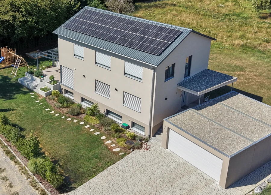 Modernes mehrstöckiges Einfamilienhaus mit Solarpanelen auf dem Dach, einem schönen großen Garten und Garage.