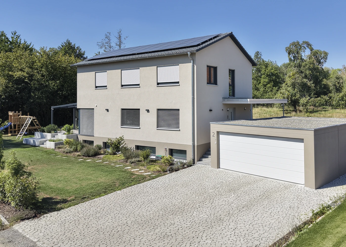 Modernes mehrstöckiges Einfamilienhaus mit Solarpanelen auf dem Dach, einem schönen großen Garten und Garage.