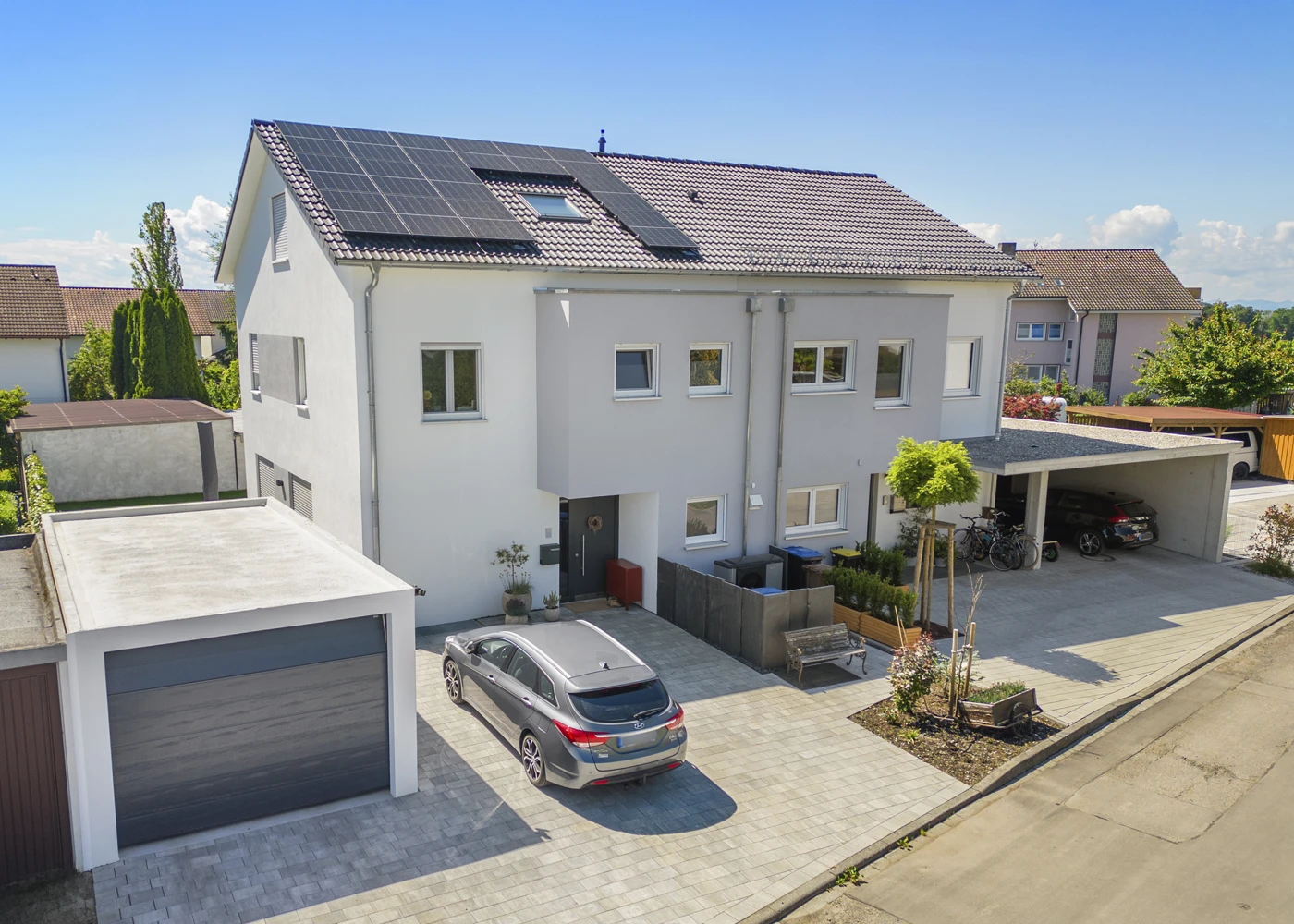 Modernes Einfamilienhaus mit Solaranlage, Garage und geparktem Auto in einer ruhigen Wohngegend.